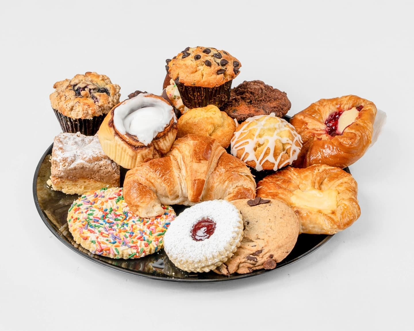 A bakery platter overflowing with fresh muffins, croissants, danishes, and cookies