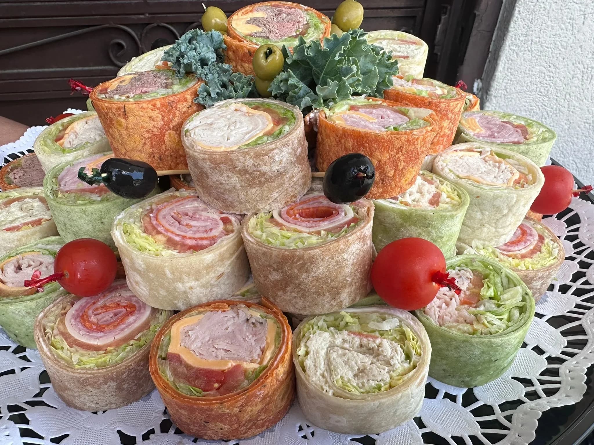 Wrap Platter from another angle — colorful tortillas wrapping our deli classics, arranged on fresh kale