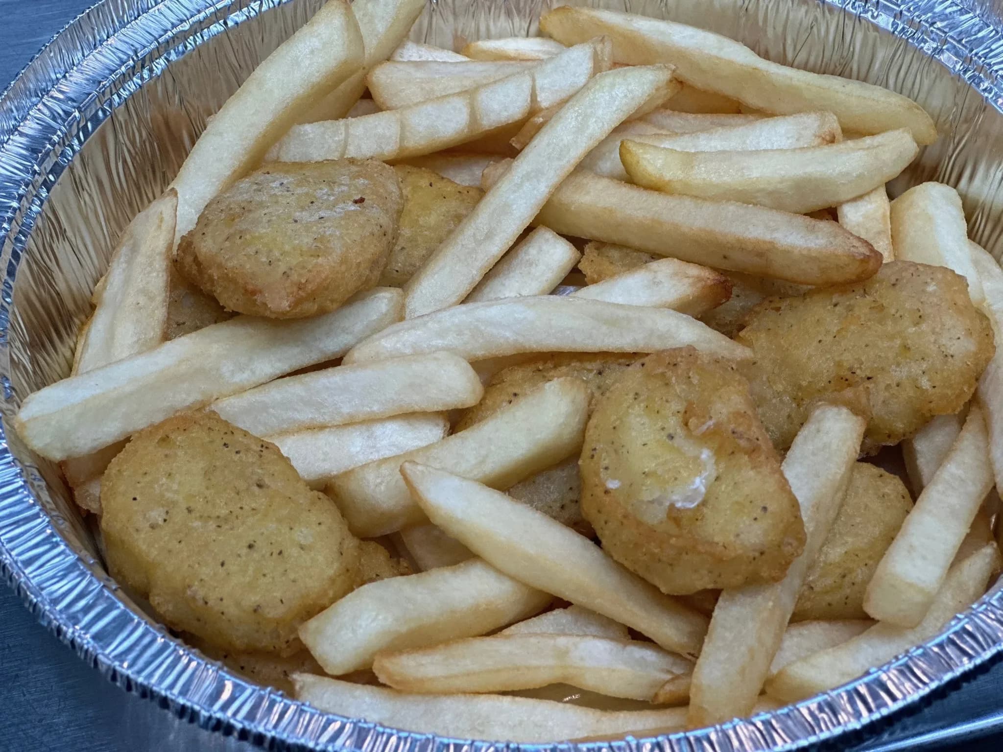 Crispy chicken nuggets piled over golden fries — pure comfort food