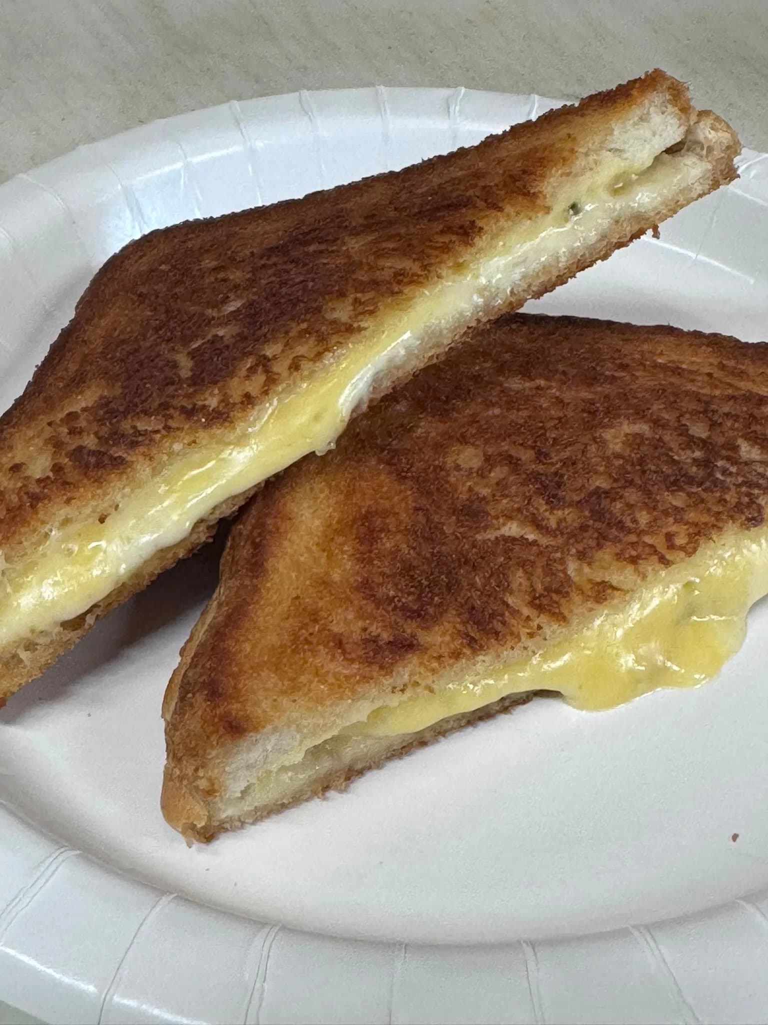 Classic grilled cheese cut in half — golden crust, cheddar oozing out the sides