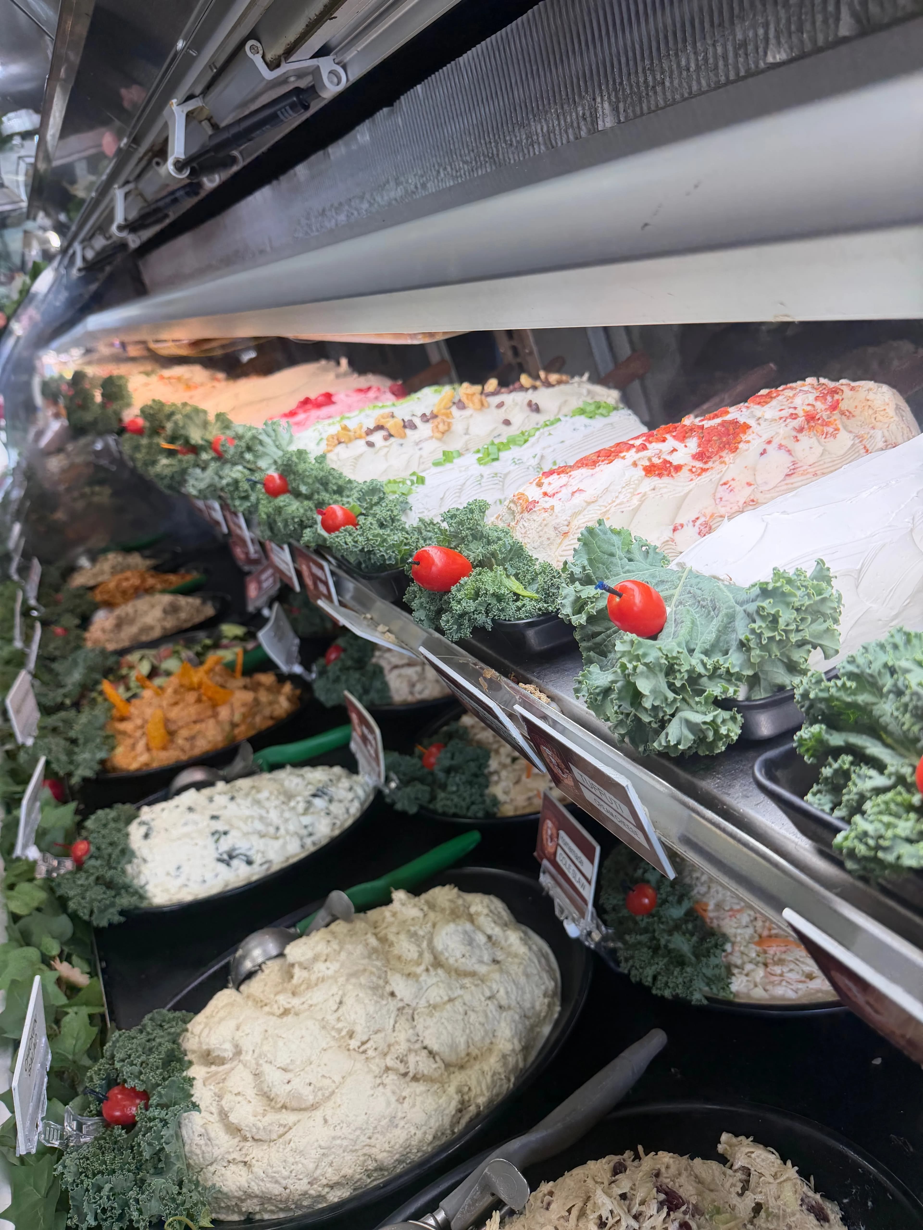 Our cream cheese case — rows of plain, scallion, veggie, lox, walnut raisin, and more