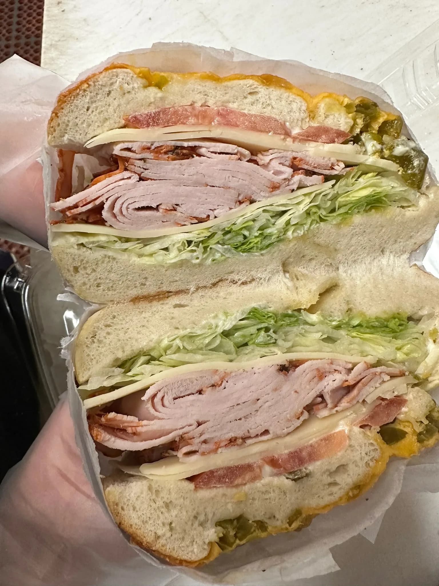 Double-stack deli sandwich layered with hand-sliced cold cuts, lettuce, and tomato