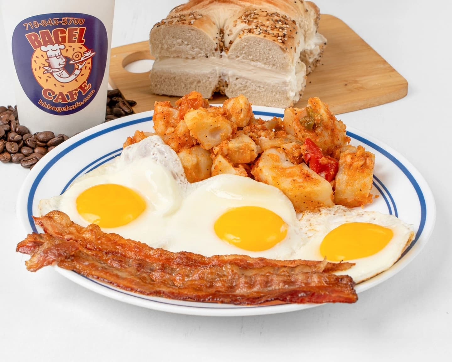 Three eggs, bacon, home fries, and an everything bagel with cream cheese — the full plate, with coffee on the side